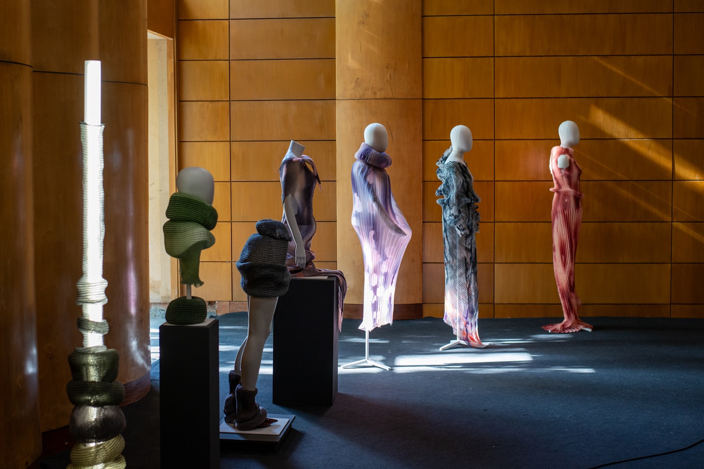 Mannequins display abstract sculptures and garments in a room.